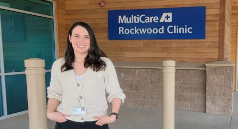 Psychiatric mental health nurse practitioner, Taylor Keating, ARNP, poses in front a building sign reading MultiCare Rockwood Clinic