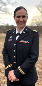 A woman in an Army dress uniform smiles at the camera