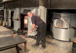 Veteran John Obermuller rolls hot glass on the work surface at the Museum of Glass