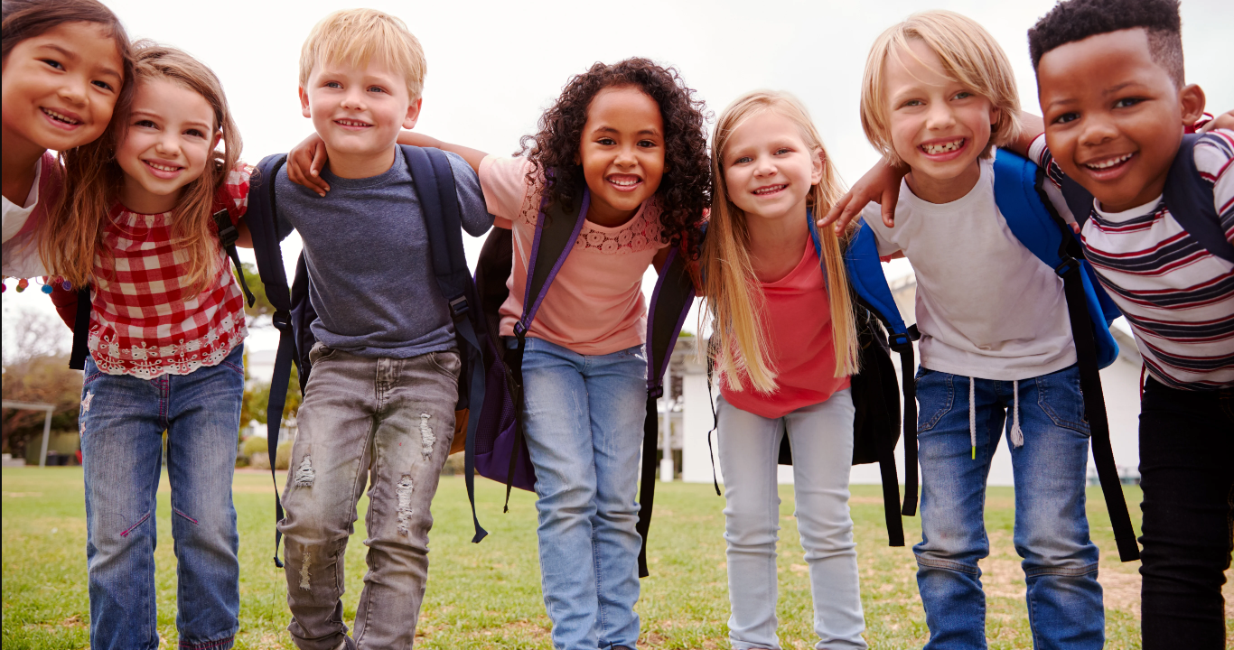Group of elementary-age children smiling with arms around each other