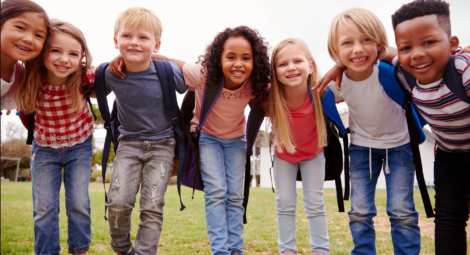 Group of elementary-age children smiling with arms around each other