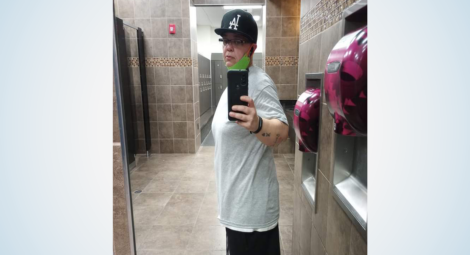 Woman in T-shirt and ball cap poses for a mirror selfie