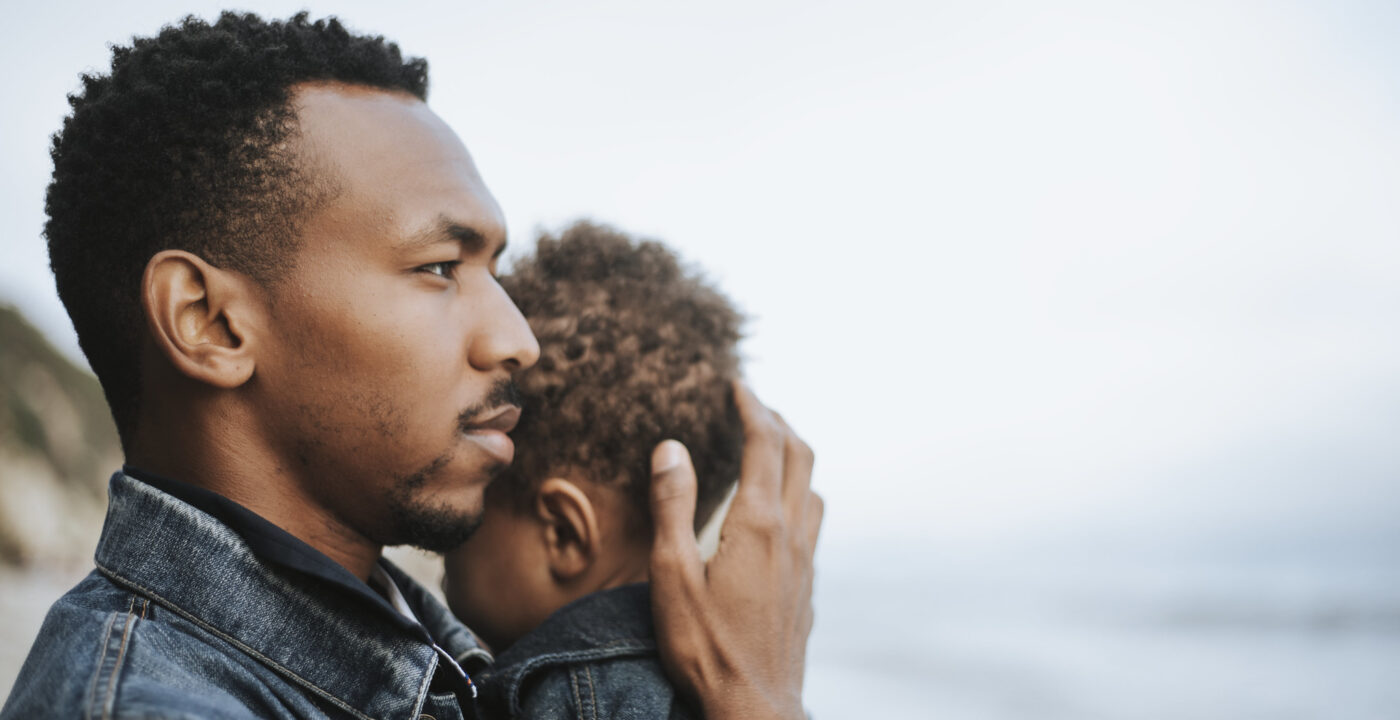 Man holds toddler while looking out at the water