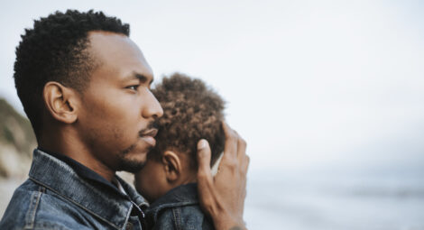 Man holds toddler while looking out at the water