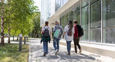 Four college students, viewed from behind, walking together on campus