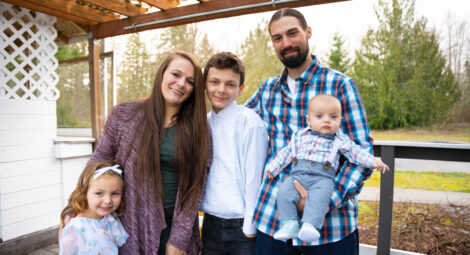 Mom, dad and three children pose on a deck outdoors