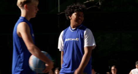 Two boys playing basketball wearing blue tank tops with MultiCare printed on the front.