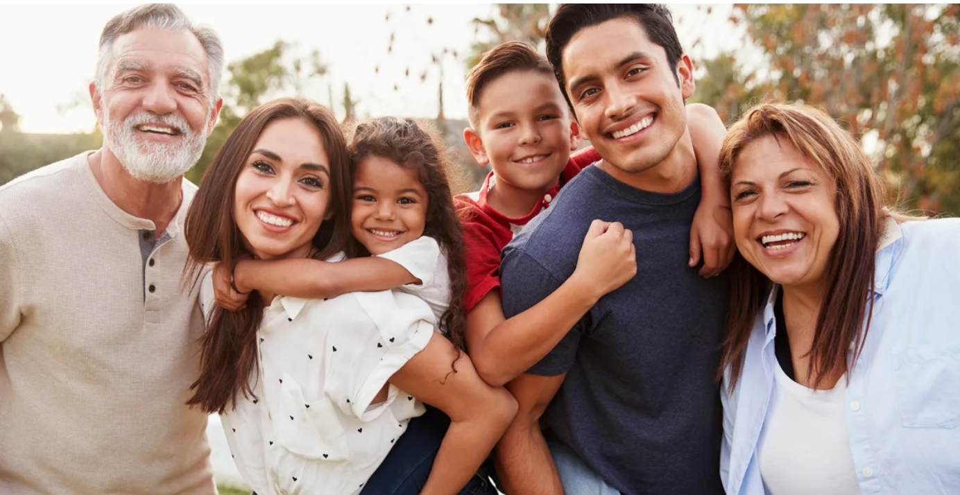 Hispanic presenting multi-generational family posing for photo in park