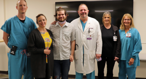 Patient, his doctor and some of his care team stand for a photo