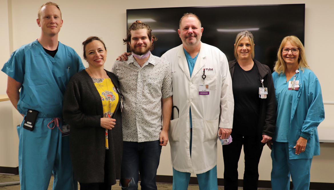 Patient, his doctor and some of his care team stand for a photo