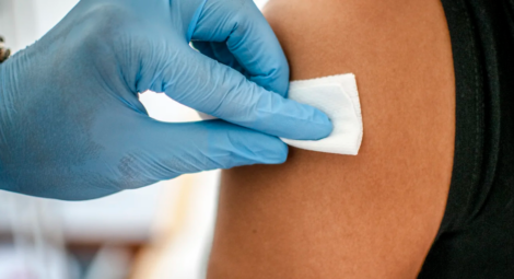 Health care provider’s gloved hand using an antiseptic wipe on a patient’s skin
