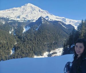 Woman poses for photo with snow-capped mountain in background