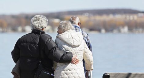 Two older women and one older man walking alongside a body of water