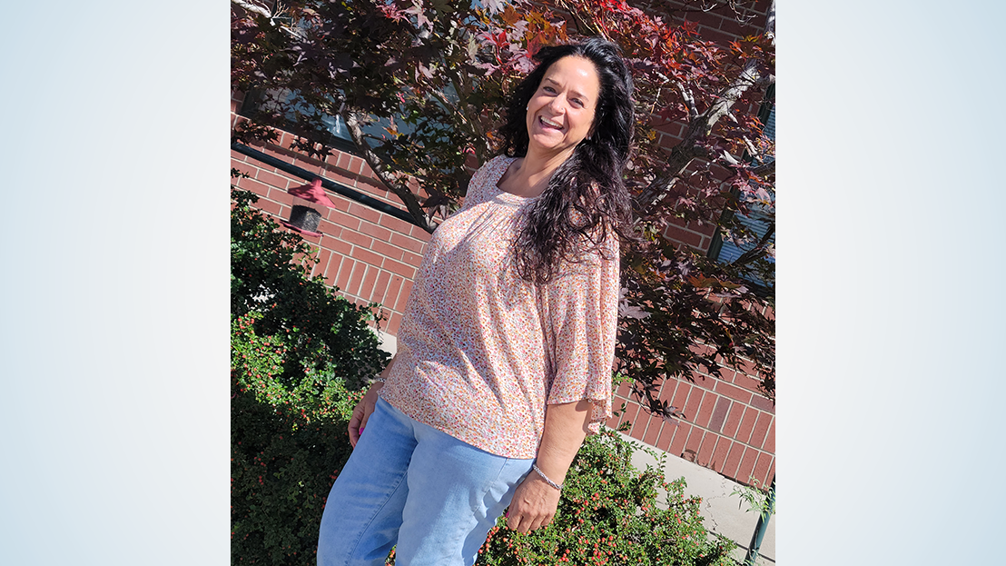 Woman posing in a pink shirt and jeans following weight loss surgery.
