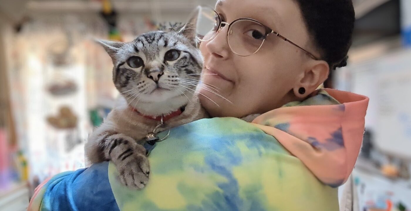 Picture of a young person in a tie-dyed sweatshirt holding a cat