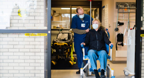 MultiCare provider guiding patient in a wheelchair out of the emergency department