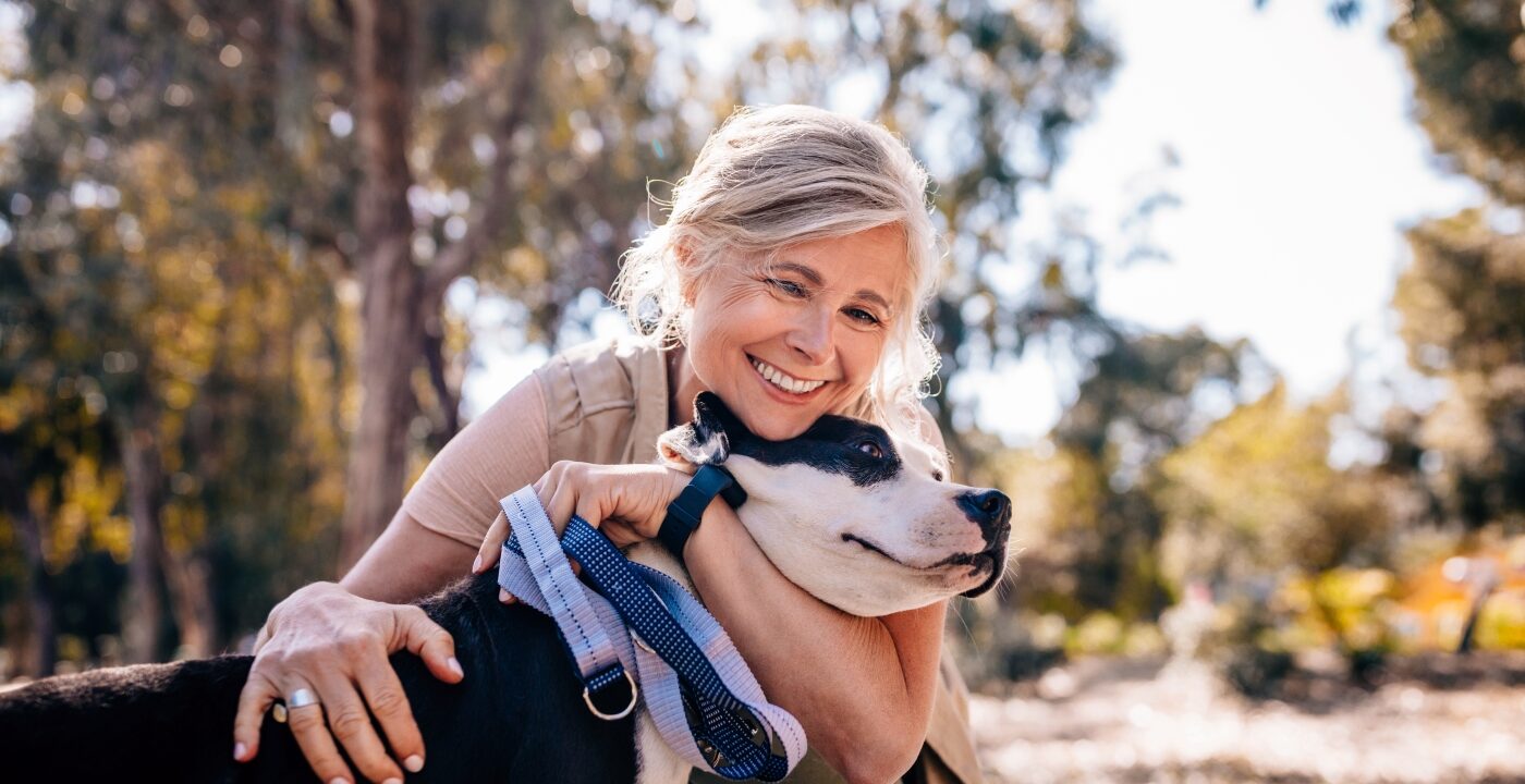 Affectionate woman embracing pet dog in nature