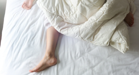 A young woman’s bare feet sticking out of a white comforter