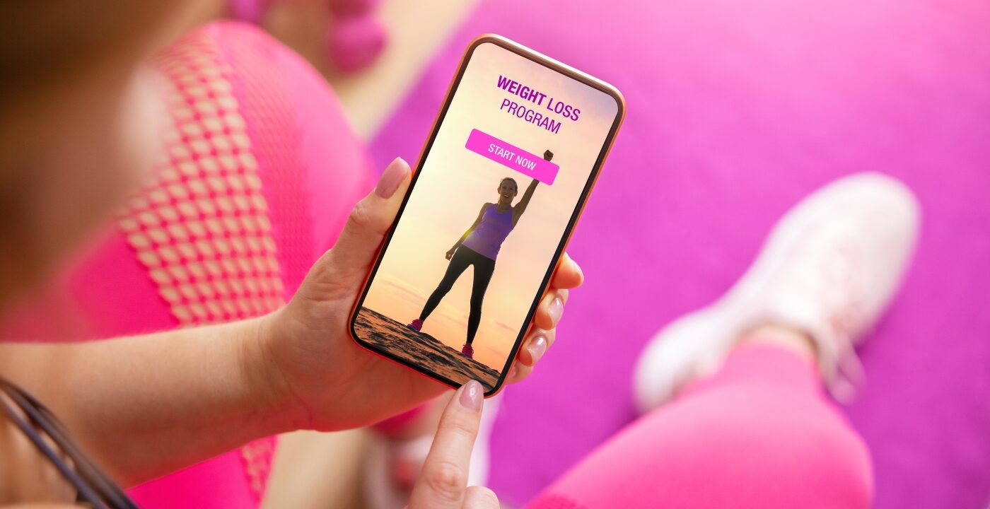 Person looking at smartphone screen with weight loss program displayed