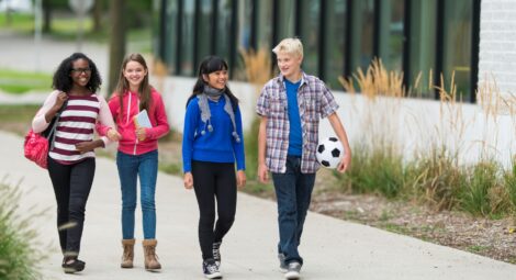 A group of preteens walk down a sidewalk