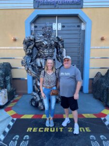 Woman and man stand in front of Transformers figure Universal Studios <Caption> Dolan with husband Mike at Universal Studios