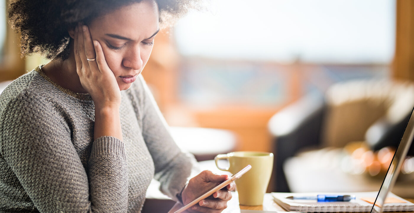 Young woman with a concerned expression reading a text on her phone