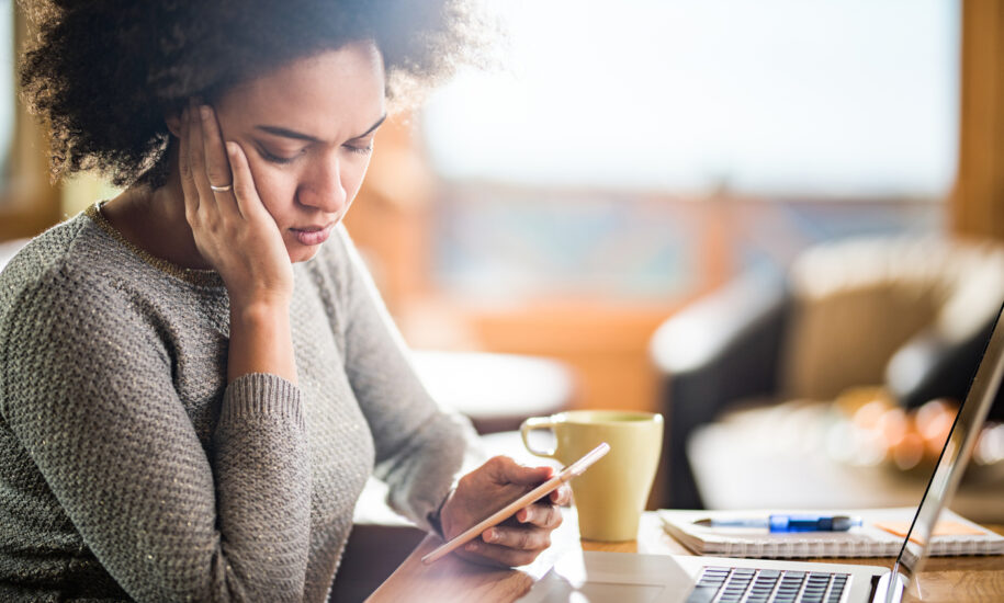 Young woman with a concerned expression reading a text on her phone