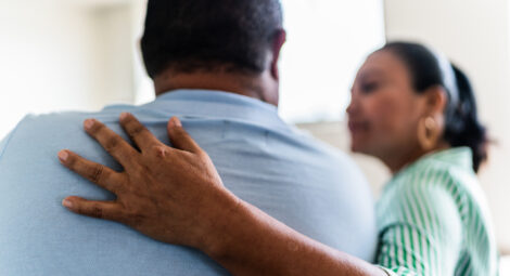 Woman puts a comforting arm around man’s shoulders