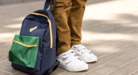 Student standing with backpack on sidewalk