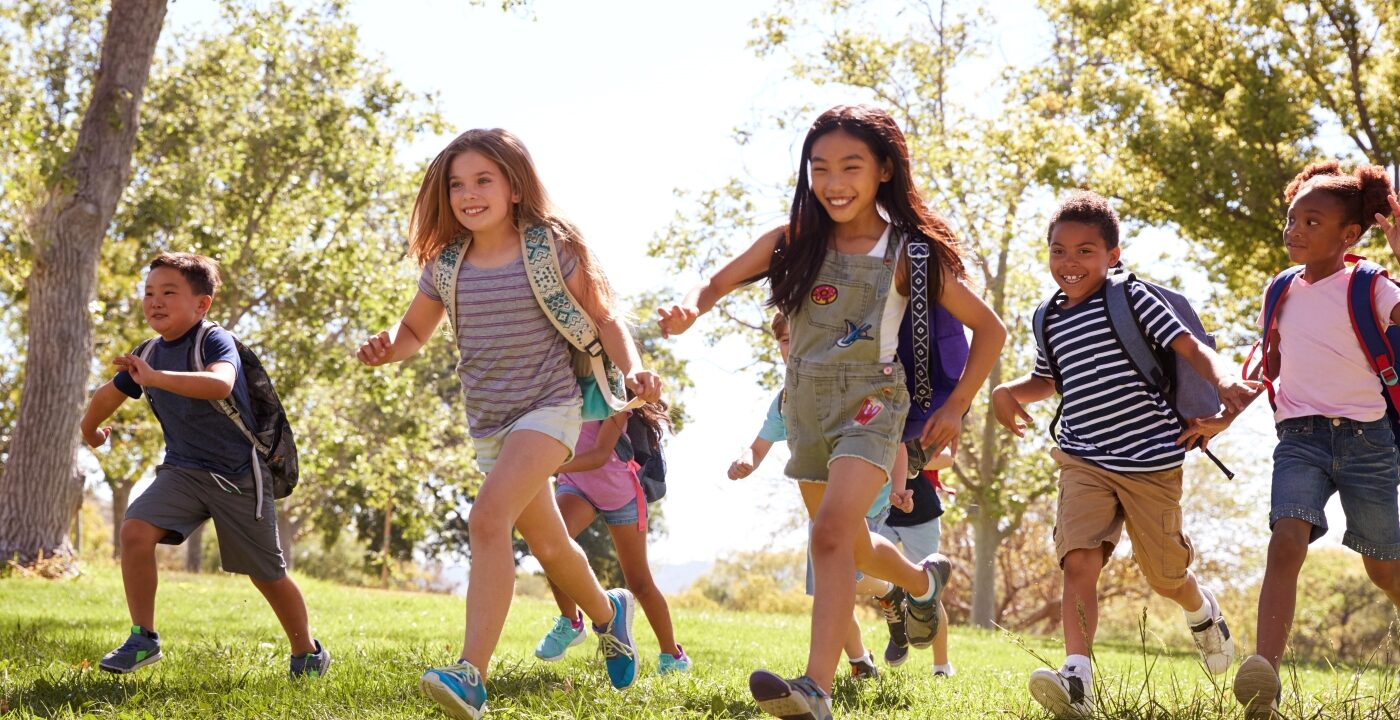Group of kids wearing backpacks running to school
