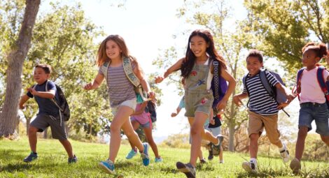 Group of kids wearing backpacks running to school