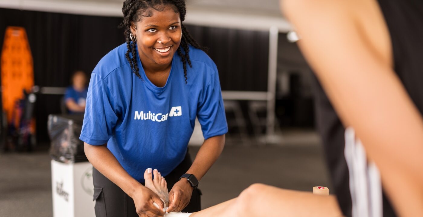 Woman in MultiCare T-shirt wraps a person’s foot in bandages