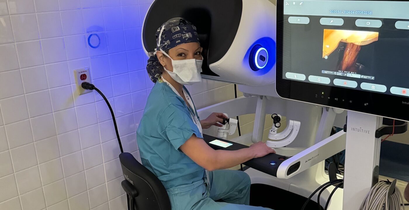 Surgeon sitting at the console of a surgical robot during a patient procedure
