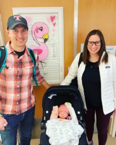 Mother and father holding baby carrier.