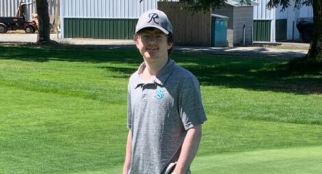 Young man wearing a baseball cap standing on a golf course