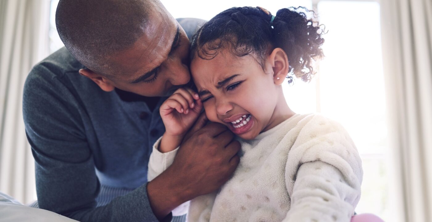 A father consoling his young daughter who is crying