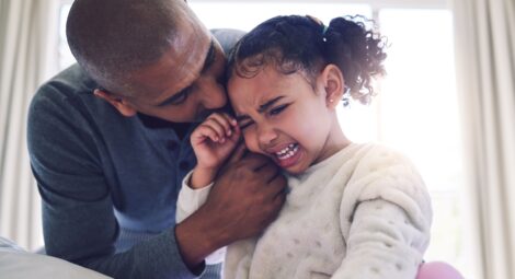 A father consoling his young daughter who is crying
