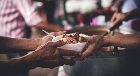 A person handing a bowl of food to another person