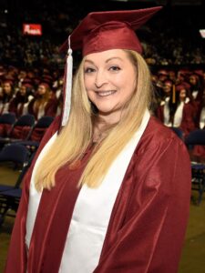 Woman smiling wearing graduation cap. 