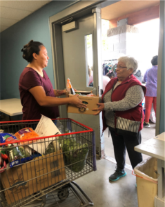 A woman helping another woman at a food bank.