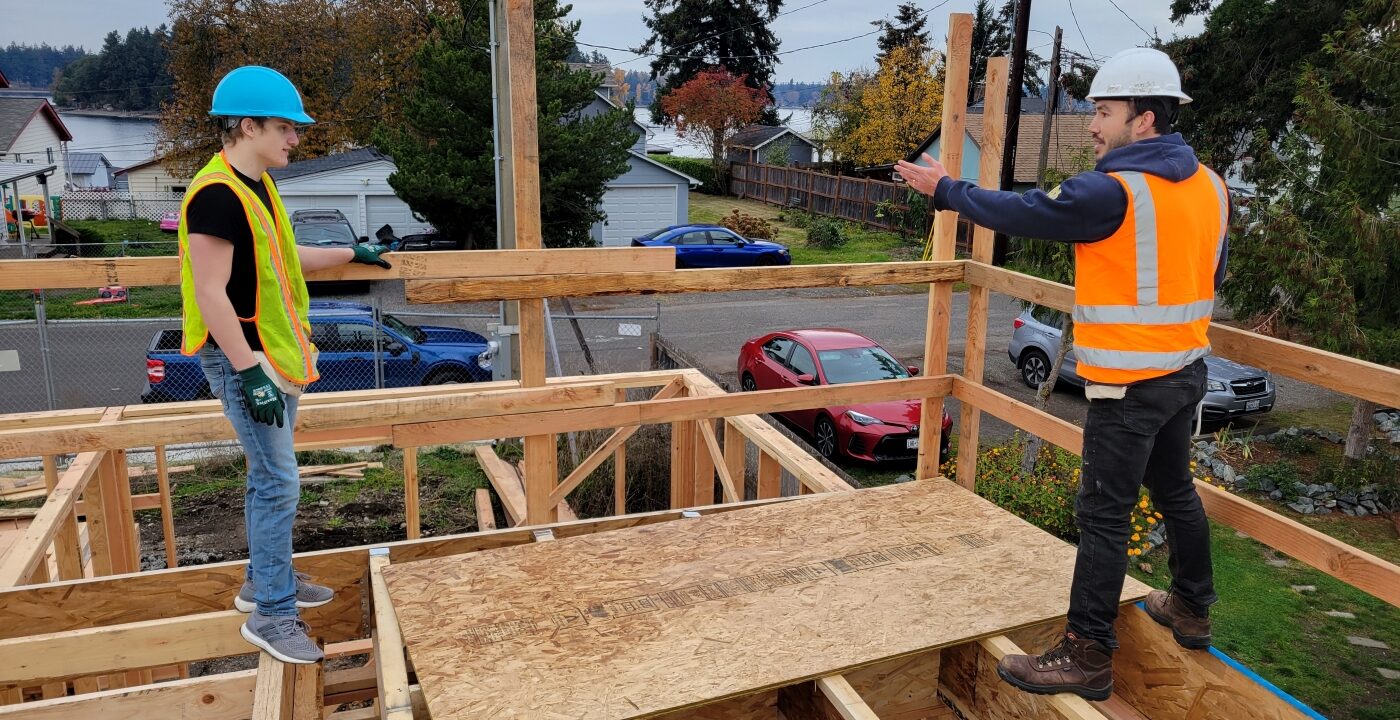 Two people stand on second floor framing of home under construction
