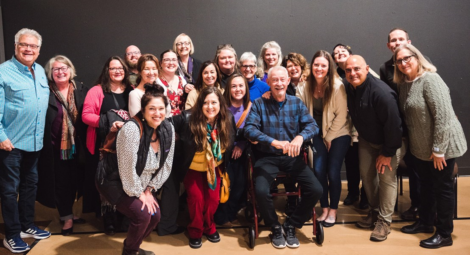 Group of adults surrounding older man in wheelchair