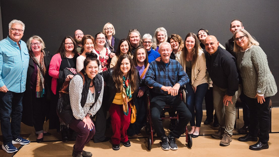 Group of adults surrounding older man in wheelchair