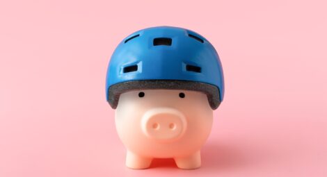 A toy pig in a blue helmet on a pink background