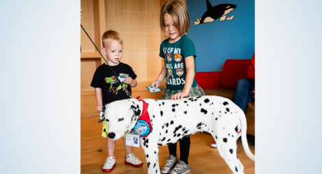 Two children petting a dalmation