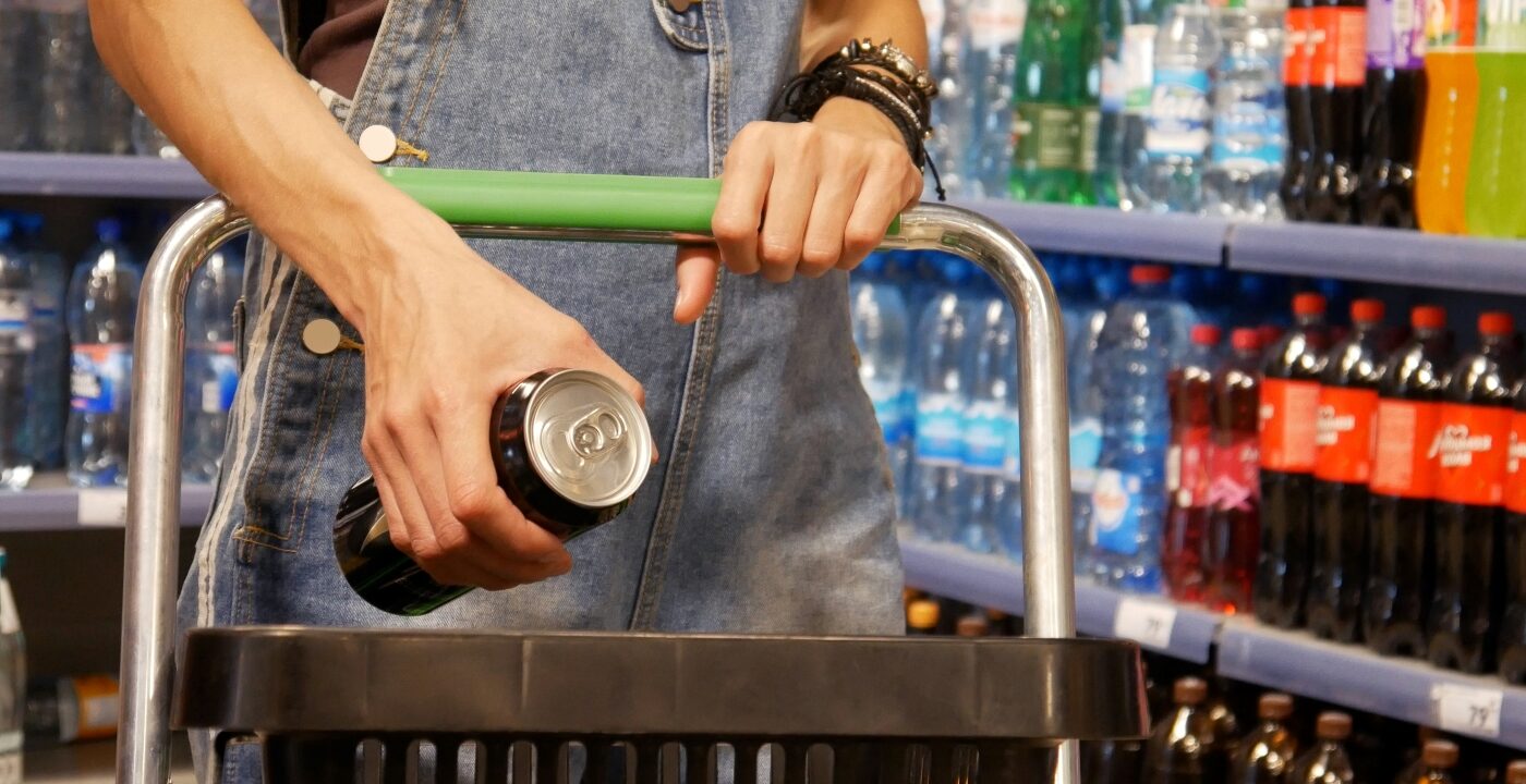 Person holding a canned energy drink while shopping