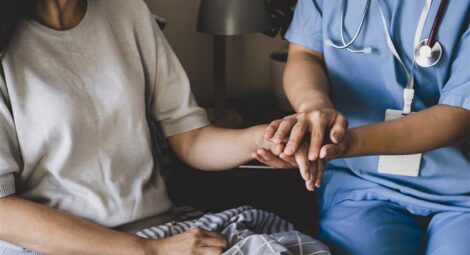 A nurse holds a patient’s hand