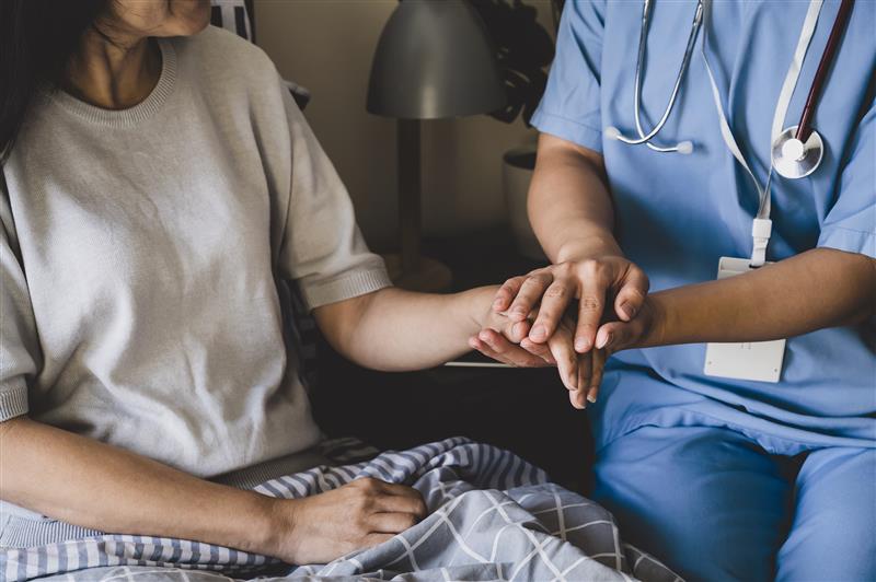 A nurse holds a patient’s hand