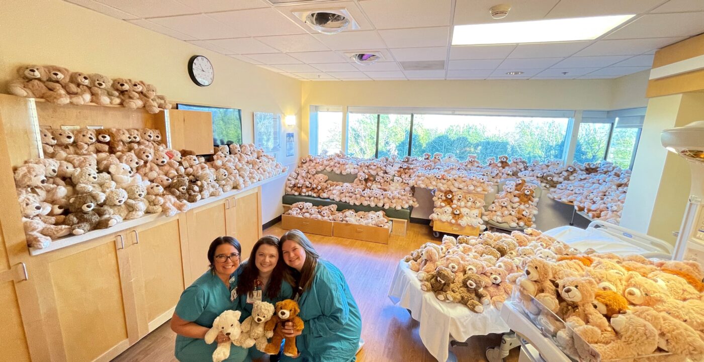 Three health care workers hold teddy bears in room filled with teddy bears