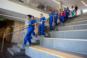 Students in scrubs walk down stairs